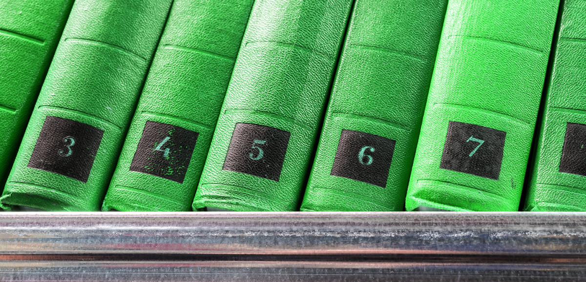 A set of green numbered books on a bookshelf.