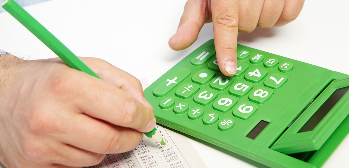 A hand holding a pencil and a calulator