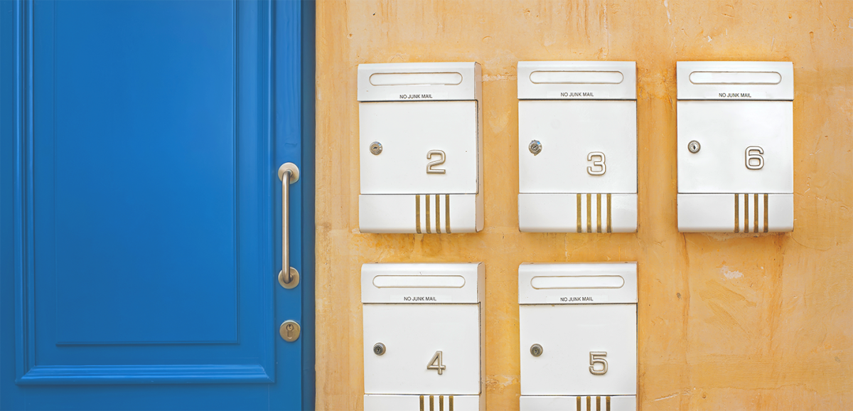 A blue door next to 5 mailboxes with numbers on them